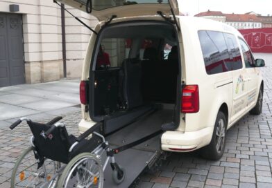 Rückseite eines Inklusionstaxis mit ausgeklappter Rampe und Rollstuhl.