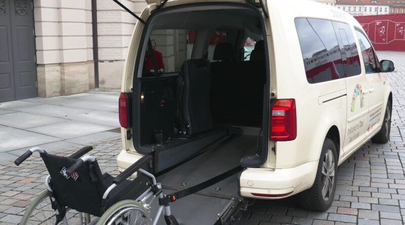 Rückseite eines Inklusionstaxis mit ausgeklappter Rampe und Rollstuhl.