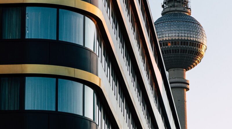 Der Berliner Fernsehturm ragt hinter einem Gebäude hervor.