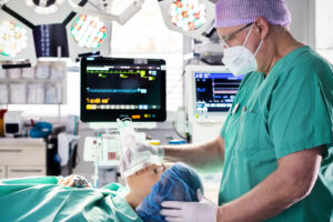 Eine liegende Patientin und rechts ein Narkosearzt.