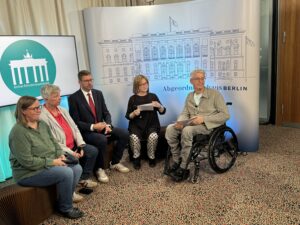 Gruppe von sechs Personen vor einer Leinwand des Abgeordnetenhauses Berlin