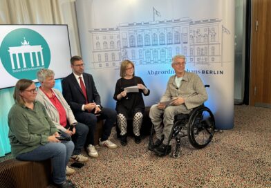 Gruppe von sechs Personen vor einer Leinwand des Abgeordnetenhauses Berlin